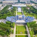 an aerial view of a stadium with raised seating surrounded by green parkland